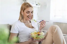 Mujer comiendo ensalada en casa.